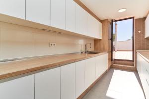 a kitchen with white cabinets and a window at El ático del Oasis in Salobreña