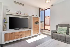 a living room with a flat screen tv and a couch at El ático del Oasis in Salobreña