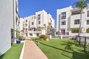 an apartment building with a lawn in front of it at El ático del Oasis in Salobreña