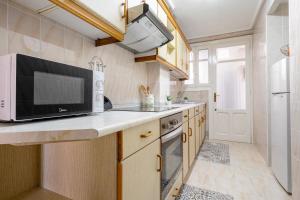 a kitchen with a microwave oven and a sink at Apartamentos El Compromiso in Caspe