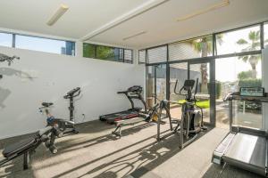 a gym with three exercise bikes and windows at Villa One on the Waterways - Pool, Spa Pool, Tennis in Whitianga