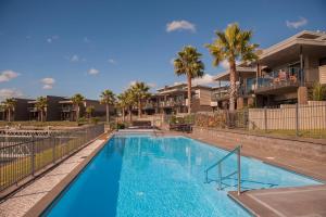 a swimming pool with palm trees and houses at Villa One on the Waterways - Pool, Spa Pool, Tennis in Whitianga