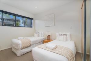 a white room with two beds and a window at Villa One on the Waterways - Pool, Spa Pool, Tennis in Whitianga +17 photos