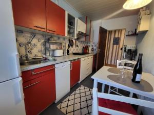 a small kitchen with red cabinets and a table with a bottle of wine at Ferienwohnung Kleine Bergluft Hahnenklee in Hahnenklee-Bockswiese
