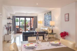 a dining room and living room with a table and chairs at Beach front apartment Mar Azul in Estepona