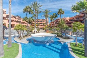 a large fountain in the middle of a pool with palm trees at Beach front apartment Mar Azul in Estepona