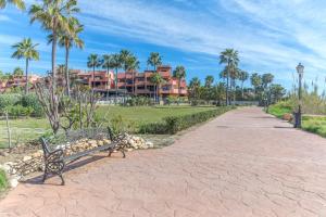a park bench sitting on a path in front of a building at Beach front apartment Mar Azul in Estepona