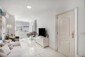 a white living room with a couch and a tv at Estrella Del Mar Amazing Loft Casa in Mogán