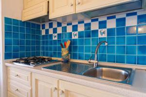 a kitchen with a sink and blue tiles at Residence La Virginia in Palau +23 photos