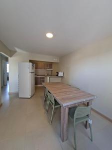 a kitchen with a wooden table and chairs and a refrigerator at El Portal Los Álamos in Rincon de los Sauces