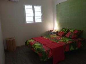 a bedroom with a bed with a red and green blanket at Gîte KAZ' A TYKA jacuzzi privatif in Saint-François