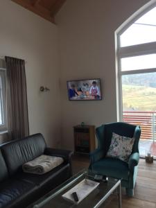 ein Wohnzimmer mit einem Sofa und einem TV an der Wand in der Unterkunft Artgerecht Ferienhäuser in Bad Berleburg