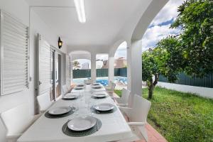 a long white table with white chairs on a patio at Villa Martins in Albufeira