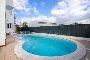 a swimming pool with blue chairs and a fence at Villa Martins in Albufeira