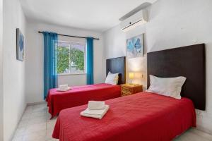 two red beds in a room with a window at Villa Martins in Albufeira +24 photos