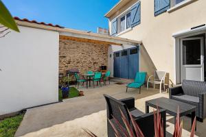 a patio with chairs and tables in front of a building at Les Passiflores - Chambre d'Hôtes in Pornic