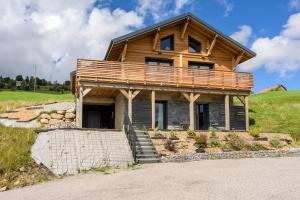 a log home with a deck on a hill at Le chalet Amélie in La Bresse