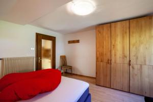 a bedroom with a red bed and wooden cabinets at Rieglhof Apartment Kükennest in Curon Venosta