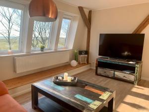 a living room with a large flat screen tv at Haevn-Erholung, Fewo Südsonne in Reußenköge