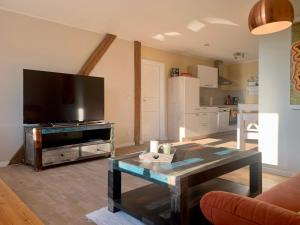 a living room with a table and a large television at Haevn-Erholung, Fewo Südsonne in Reußenköge