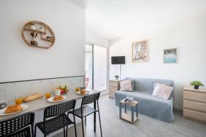 a living room with a table and chairs and a couch at Plage et Soleil Parking Privé Piscine Plage à 5 min in La Grande Motte