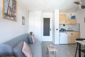 a living room with a blue couch and a kitchen at Plage et Soleil Parking Privé Piscine Plage à 5 min in La Grande Motte +33 photos