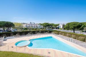 a large swimming pool next to a patio with chairs at Plage et Soleil Parking Privé Piscine Plage à 5 min in La Grande Motte