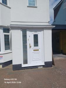 a white house with a white door with a window at Christian Guest House 1 in Luton