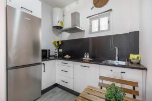 a kitchen with white cabinets and a stainless steel refrigerator at Casa Abuela Maria in Jerez