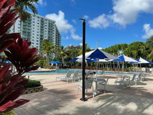 a group of chairs and tables with umbrellas next to a pool at Apartments Miami in Sunny Isles Beach
