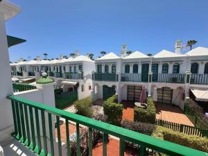 a large white house with a green fence at Dunaflor Gemelo 2 in San Bartolomé