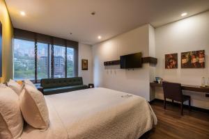 a hotel room with a large bed and a desk at Diez Hotel Categoría Colombia in Medellín