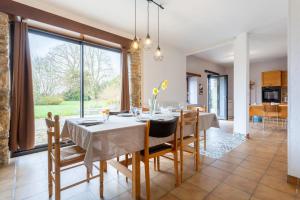 a dining room with a table and chairs and a large window at La longère familiale et authentique in Melgven