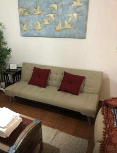 a couch with two red pillows in a living room at Casa Jubileu in Golegã