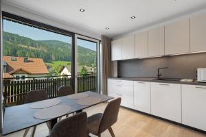 a kitchen with a table and chairs and a large window at Premium App Hofer Heidi in Villabassa