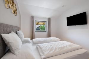 a white bedroom with a bed and a flat screen tv at Premium App Hofer Heidi in Villabassa