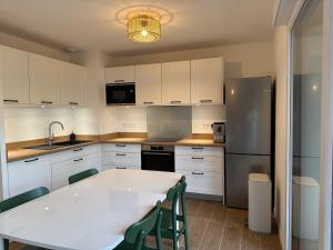 a kitchen with a white table and a refrigerator at Appartement Autza 6 voyageurs proche des plages in Moliets-et-Maa