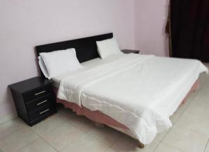 a bedroom with a large white bed with a night stand at شاطئ الحوية in Taif