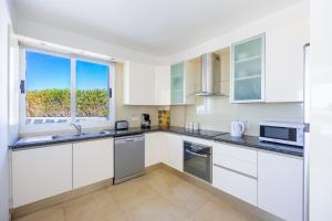 a kitchen with white cabinets and a large window at Villa Bella Ena in Nea Dimmata