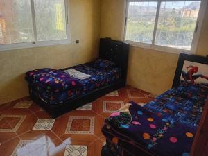 a room with a couch and a bed and windows at شقة الياس in Agdz