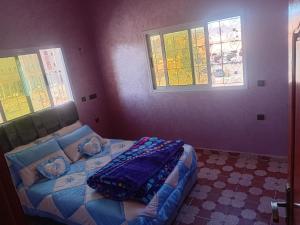 a bedroom with a bed and two windows at شقة الياس in Agdz