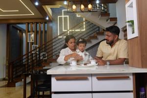 a man and two children sitting at a kitchen counter at CRK Home Stays in Cochin