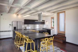 a kitchen with a black table and yellow chairs at Ca Bosca - Fine Living in Torri del Benaco