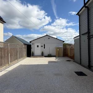 a garage with a white building and a fence at The Annexe Long Melford in Long Melford