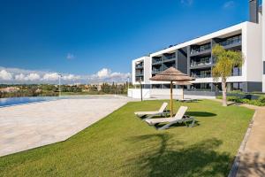 two chairs and an umbrella on a lawn in front of a building at Luxury T2 Apartment With Ocean View in Portimão