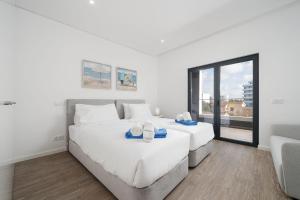 two beds in a white room with a window at Luxury T2 Apartment With Ocean View in Portimão +23 photos