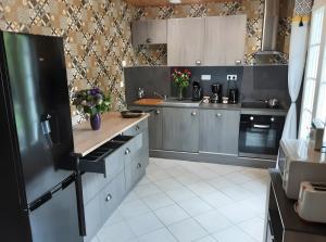 a kitchen with gray cabinets and a black refrigerator at Gîte de Lonzanges in Lanobre