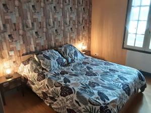 a bedroom with a bed with a blue and white comforter at Gîte de Lonzanges in Lanobre