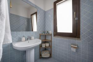 ein blau gefliestes Badezimmer mit Waschbecken und Spiegel in der Unterkunft Flat Arcipelago in Palau + 18 Fotos