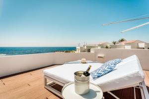 a balcony with a bed and a table with a bottle of wine at Binibeca Sunset in Sant Lluis